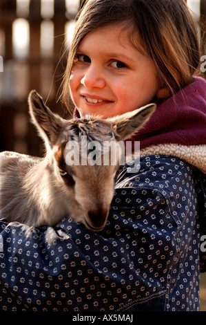 Mädchen hält eine Neugeborene Ziege (Capra) in ihre Arme, Othensdorf, Mecklenburg-Western Pomerania, Deutschland, Europa Stockfoto