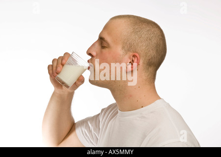 Junger Mann, ein Glas Milch trinken Stockfoto