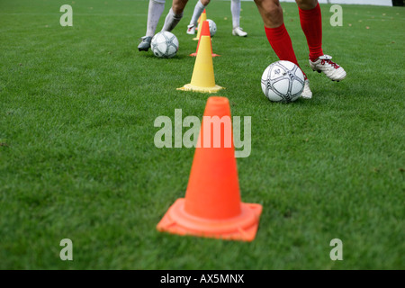 Fußball-Spieler laufen Slalom mit Fußball rund um Marken Stockfoto