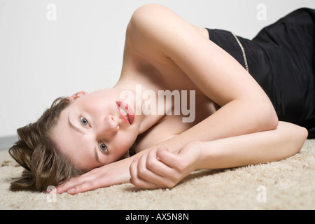 Porträt einer jungen Frau, die auf dem Teppich Verlegen Stockfoto