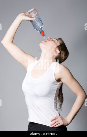 Junge Frau trinken aus einer Flasche Wasser während des Trainings Stockfoto