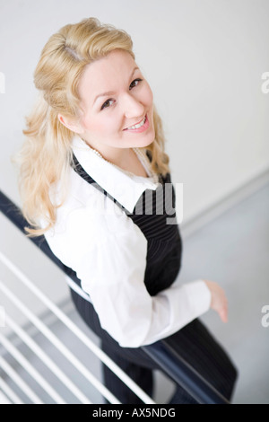 Geschäftsfrau lehnt sich an ein Geländer auf der Suche nach oben in die Kamera Stockfoto