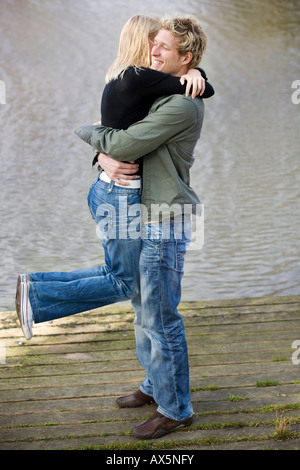 Mann, die Frau auf einem hölzernen Dock heben Stockfoto