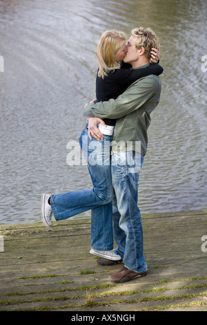 Mann Frau auf einem hölzernen Dock heben, küssen Stockfoto