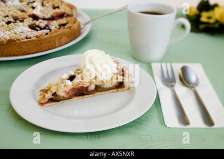 Bröckeln Pflaumenkuchen mit Schlagsahne und Kaffee serviert Stockfoto