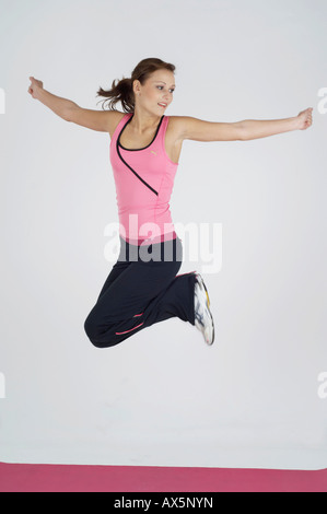 Junge Frau springt in die Luft während des Trainings Stockfoto