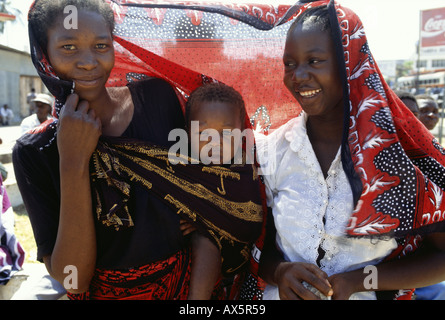 Tansania, Afrika. Frau mit Baby in einem hellen farbigen gedruckten Baumwolltuch gebunden. Stockfoto