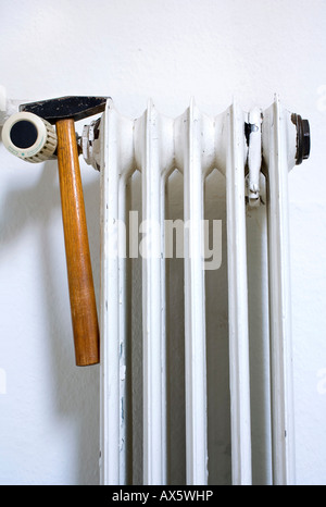 Alte Heizkörper, abblätternde Farbe und einem Hammer: symbolisches Bild für die Reparatur und Heizkosten Stockfoto