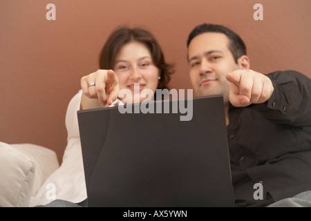 Junges Paar sitzt vor Laptop auf den Betrachter gerichtet Stockfoto