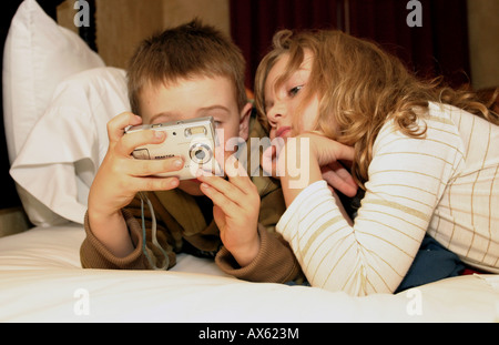 2 Kinder betrachten Bilder auf einer Digitalkamera während im Bett Stockfoto