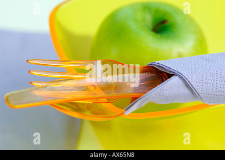 Plastikbesteck, Plastikschüssel und grüner Apfel Stockfoto