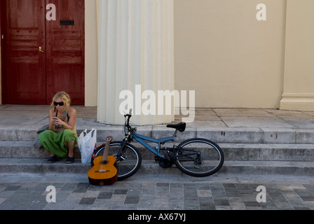 Ein junges Mädchen sitzt mit ihrem Fahrrad und Gitarre auf Schritte in Brighton North Laines England UK Stockfoto