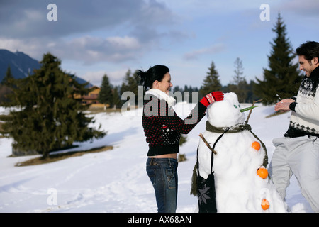 Junges Paar macht einen Schneemann Stockfoto
