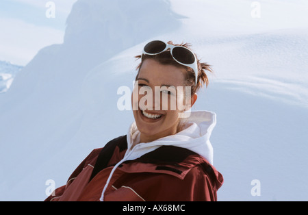Junge Frau sitzt im Schnee, lächelnd, Nahaufnahme Stockfoto