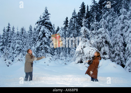 Paar mit Weihnachtsgeschenk im Schnee spielen Stockfoto