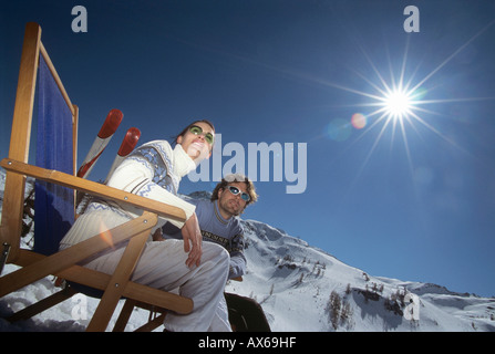 Paar sitzt auf Liegestühlen im Schnee, niedrigen Winkel Ansicht Stockfoto