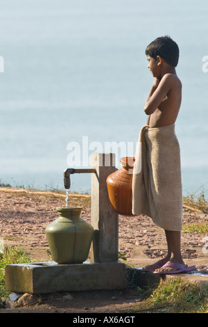 Junge, Wasser aus einem Brunnen in der Nähe des Ozeans in Varkala Südindien Stockfoto