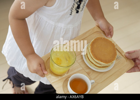 Ein Mädchen mit einem Tablett mit einigen Pfannkuchen Stockfoto