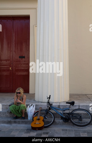 Ein junges Mädchen sitzt mit ihrem Fahrrad und Gitarre, während eine SMS auf ihr Mobiltelefon Brighton England UK Stockfoto