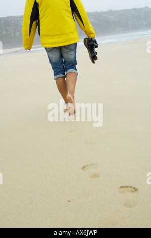 Rückansicht der Frau zu Fuß am Strand Stockfoto
