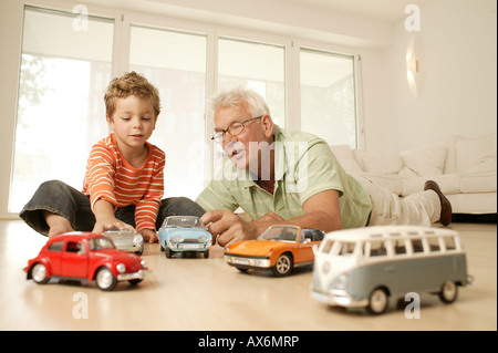 Ältere Mann und sein Enkel spielen mit Auto Stockfoto