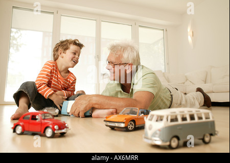 Ältere Mann und sein Enkel spielen mit Auto Stockfoto
