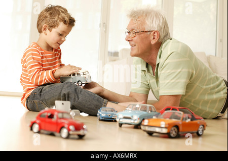 Ältere Mann und sein Enkel spielen mit Auto Stockfoto