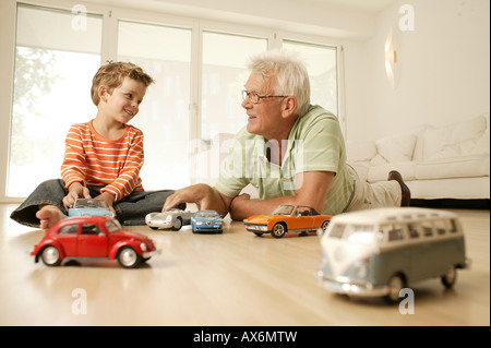 Ältere Mann und sein Enkel spielen mit Auto Stockfoto