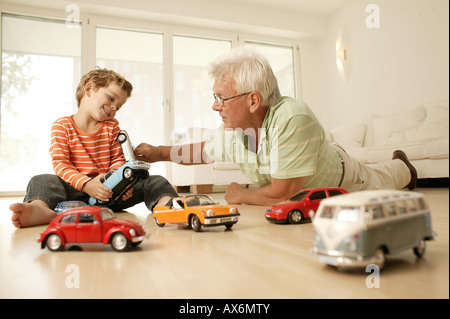 Ältere Mann und sein Enkel spielen mit Auto Stockfoto