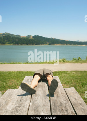 Mann auf einem Picknick-Tisch liegend Stockfoto