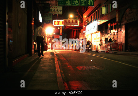 Ein Mann geht auf eine Straße im Zentrum von Hongkong schwach beleuchtet von Leuchtreklamen Stockfoto