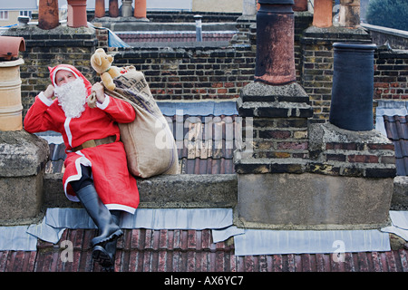 Weihnachtsmann sitzt auf einem Dach Stockfoto