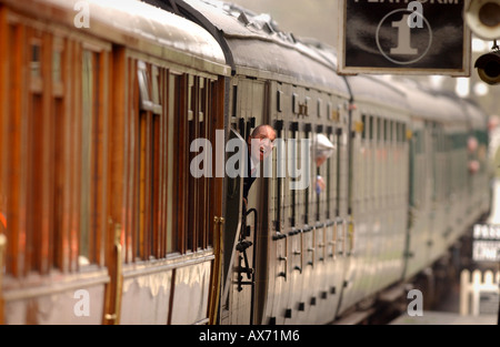 Auf der Bluebell Railway lacht East Sussex, ein unbeschwerter Dirigent aus einem abfahrenden Zug. Stockfoto