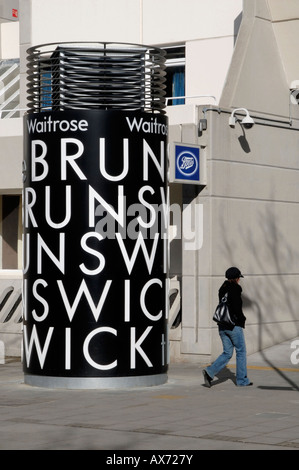 Zylindrische Schild am Eingang zum Brunswick Centre mit jungen Frau in GAP vorbei, Marchmont Street, Bloomsbury, London Stockfoto