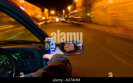 Trinken Sie, fahren Sie nachts, während Sie eine Dose Bier in der Hand halten, und zeigen Sie bei Zeitlupenaufnahmen verwackelte Lichter Stockfoto