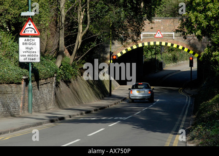 Niedrige Bogenbrücke mit Warnschild und gut sichtbare Markierungen und wartenden Wagen bei Rotlicht, Cheam, Südlondon, Surrey Stockfoto