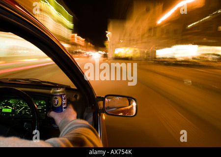 Trinken Sie, fahren Sie nachts, während Sie eine Dose Bier in der Hand halten, und zeigen Sie bei Zeitlupenaufnahmen verwackelte Lichter Stockfoto