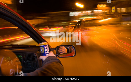 Trinken Sie, fahren Sie nachts, während Sie eine Dose Bier in der Hand halten, und zeigen Sie bei Zeitlupenaufnahmen verwackelte Lichter Stockfoto