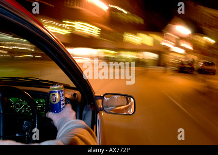 Trinken Sie, fahren Sie nachts, während Sie eine Dose Bier in der Hand halten, und zeigen Sie bei Zeitlupenaufnahmen verwackelte Lichter Stockfoto