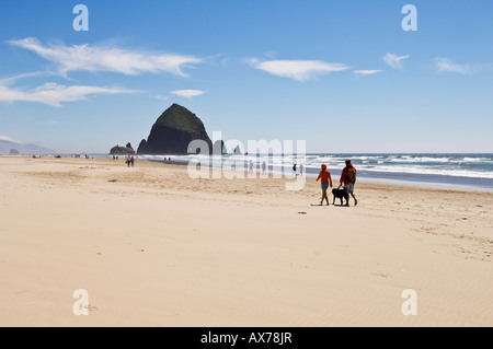 Paar walking Hund am Strand in der Nähe von Haystack Rock Cannon Beach an der Küste Oregons Stockfoto