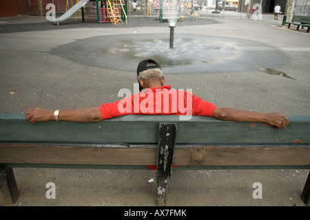 Älterer Mann auf einer Bank auf einem Spielplatz auf der unteren Ostseite von Manhattan Nickerchen Stockfoto