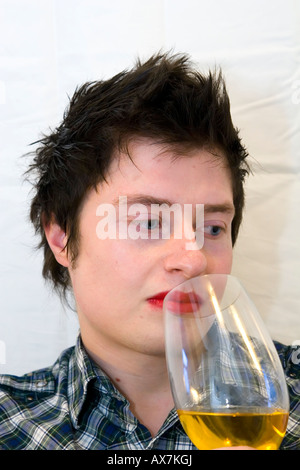 Gentleman mit leuchtend roten Lippenstift und ein Trinkglas mit Orange gefärbte Flüssigkeit im Inneren. Schwarze kurze Haare. Stockfoto