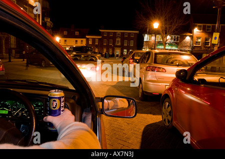 Trinken Sie, fahren Sie nachts, während Sie eine Dose Bier in der Hand halten, und zeigen Sie bei Zeitlupenaufnahmen verwackelte Lichter Stockfoto