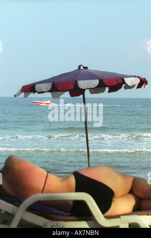 Eine Frau liegend auf einer Sonnenliege am Chaweng Noi Beach, Koh Samui. Mit Blick auf den Ozean mit Speed-Boot Rennen vorbei in der Ferne Stockfoto