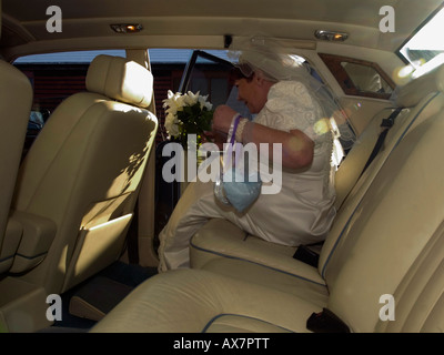 Fett Braut gerade geheiratet Eingabe ihr Brautauto mit weißem Lederinterieur nimmt sie zur Hochzeitsfeier. Stockfoto