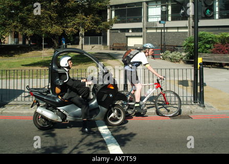 London-Mann im Büro Anzug einen Motorroller warten an der Ampel neben Radfahrer fahren Stockfoto