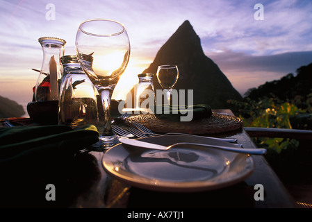 Eine Tabelle wird auf der Terrasse des Restaurant Dasheene am Sonnenuntergang, Soufrière, St. Lucia, Karibik verlegt. Stockfoto