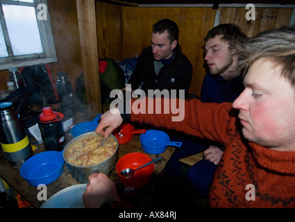 Die Ausbilder haben eine warme Hütte für eine Basis, während die Schüler im Schnee Loch überleben wöchentlich dänischen Spezialeinheiten Sirius Hund Leben Stockfoto
