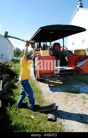 Teenager teilt Holzscheite für den Einsatz in laufen einen Dampfantrieb Traktor Stockfoto