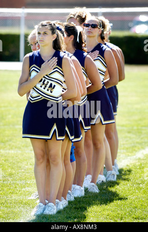 Cheerleader sagen, dass sie der US-Flagge Treue schwören, während des Fußballspiels Routine ausführen, die Verletzungen riskiert Stockfoto